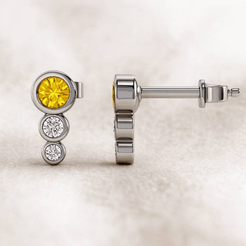 Gold earrings with yellow gemstone on a light background