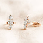 Rose gold earrings with clear gemstones on a soft beige background