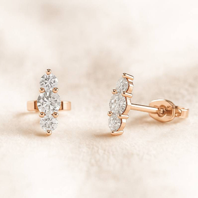 Rose gold earrings with clear gemstones on a soft beige background