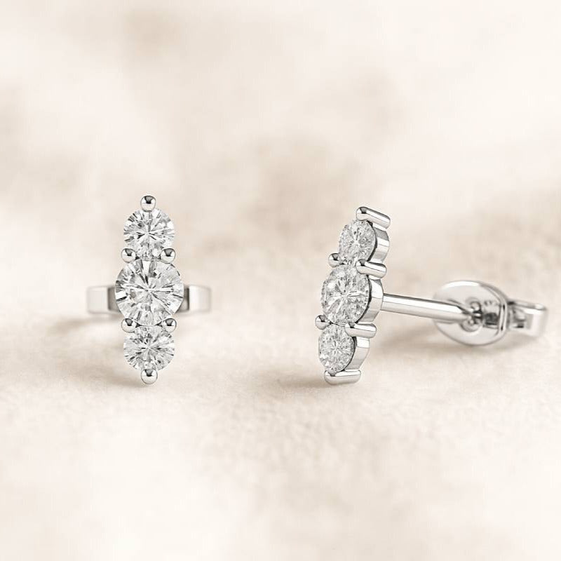 Pair of diamond earrings on a soft beige background
