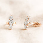 Rose gold earrings with clear gemstones on a soft beige background