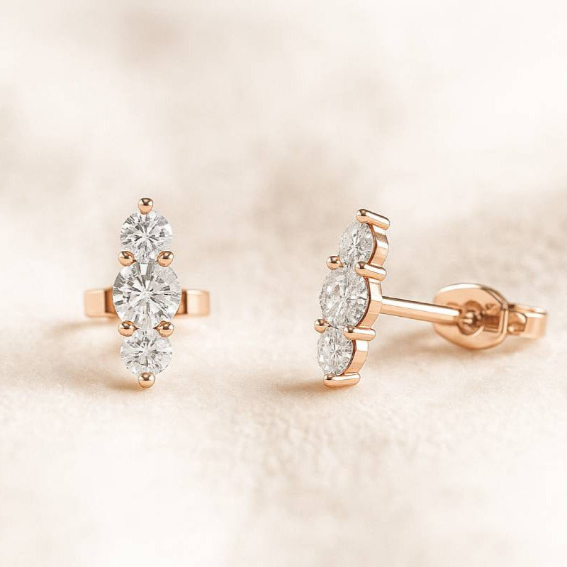Rose gold earrings with clear gemstones on a soft beige background