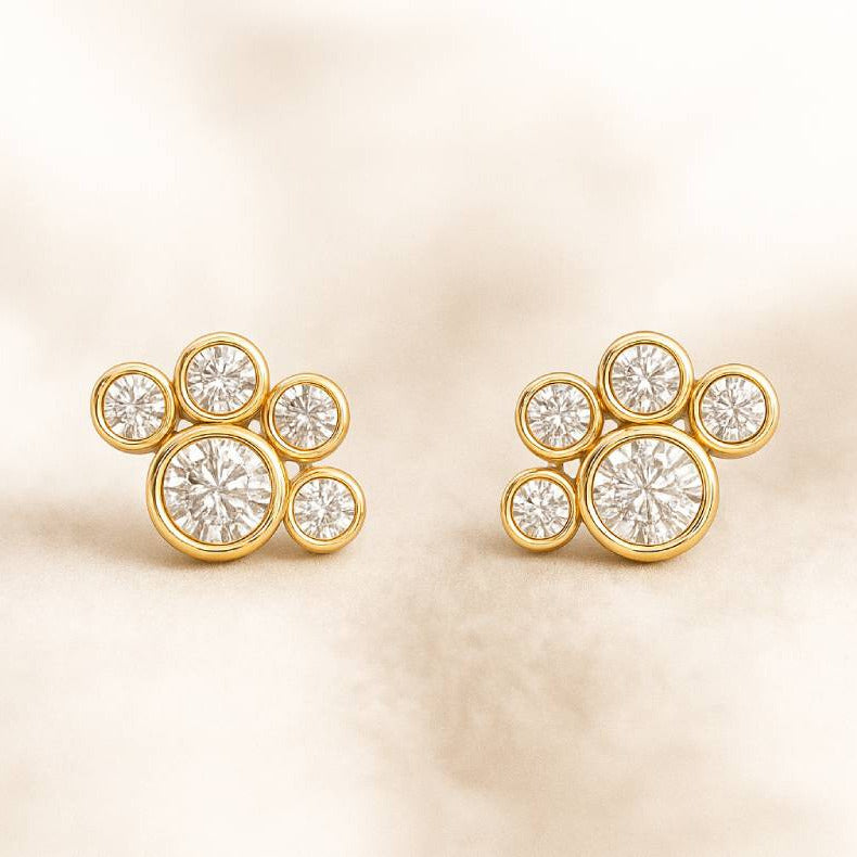 Gold earrings with diamond-like stones on a beige background