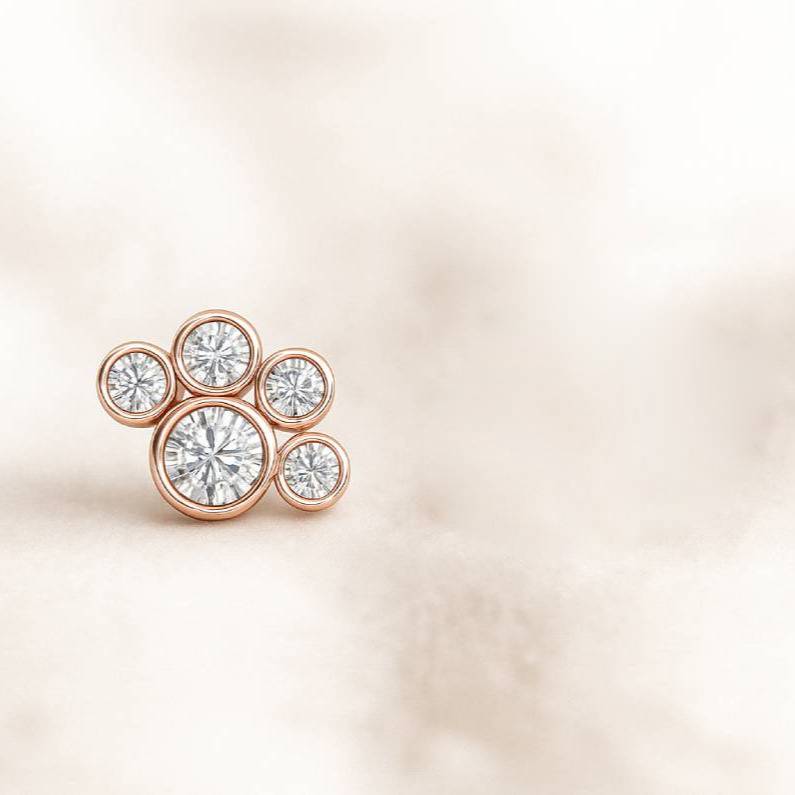 Rose gold earring with multiple diamonds on a light beige background