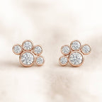 Rose gold earrings with clear gemstones on a soft beige background