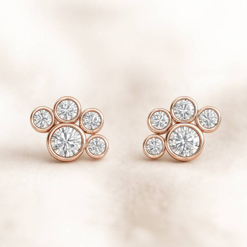 Rose gold earrings with clear gemstones on a soft beige background