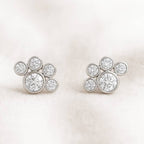 Pair of gold earrings with circular diamonds on a light pink background