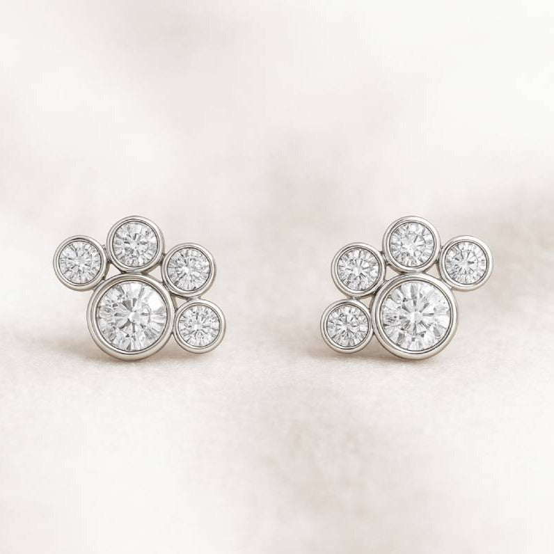 Pair of gold earrings with circular diamonds on a light pink background