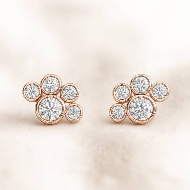 Rose gold earrings with clear gemstones on a soft beige background