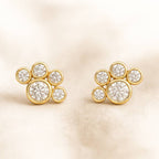 Gold earrings with diamond-like stones on a beige background