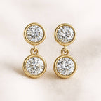 Gold earrings with clear gemstones on a light background