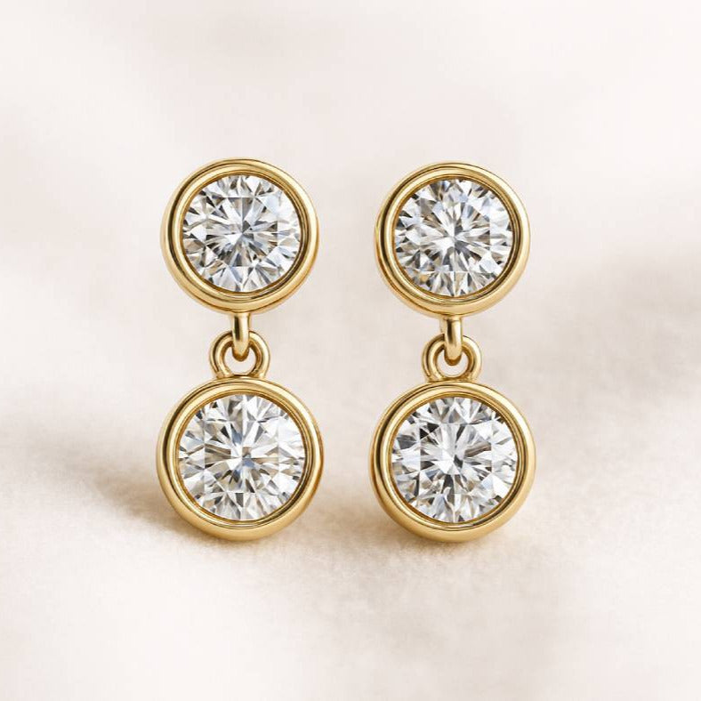 Gold earrings with clear gemstones on a light background