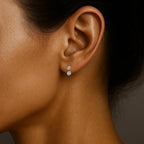 Close-up of a woman's ear wearing a diamond earring against a neutral background