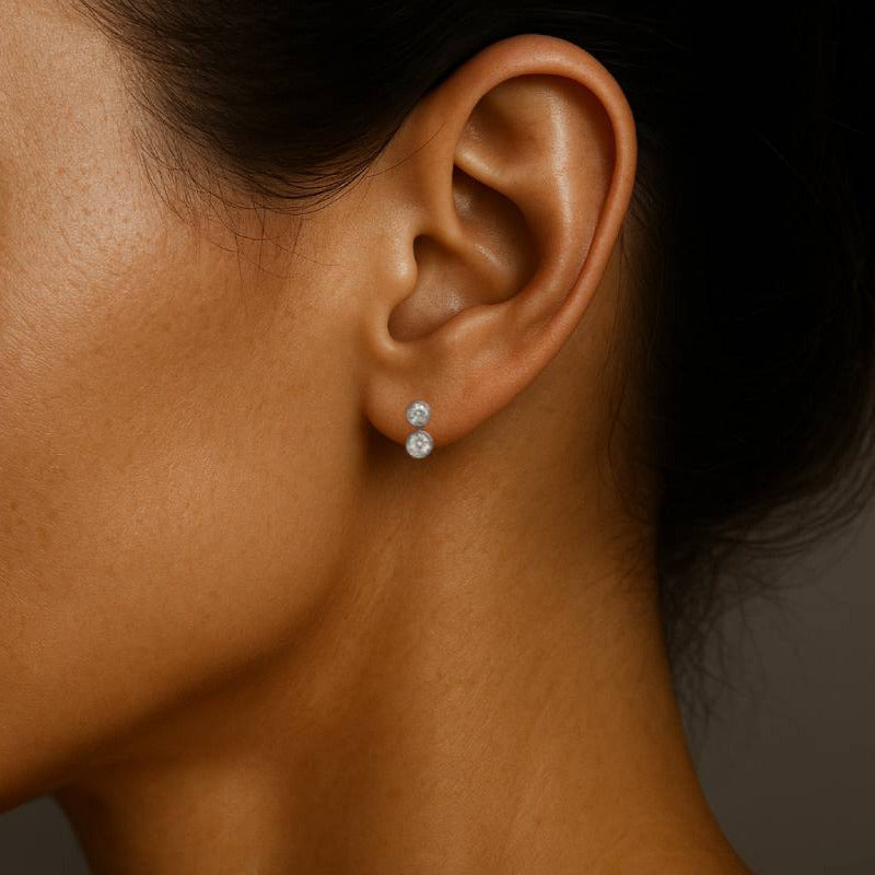 Close-up of a woman's ear wearing a diamond earring against a neutral background