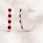 Pair of earrings with red sapphire on a beige background