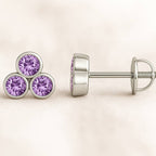 Gold earrings with purple sapphire on a beige background