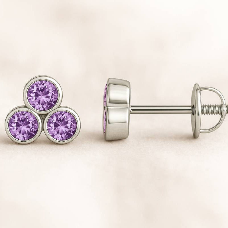 Gold earrings with purple sapphire on a beige background