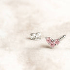 Pink gemstone stud earrings on a light pink background
