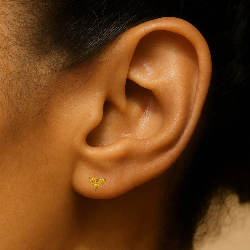 Close-up of an ear wearing a gold earring with a yellow center.