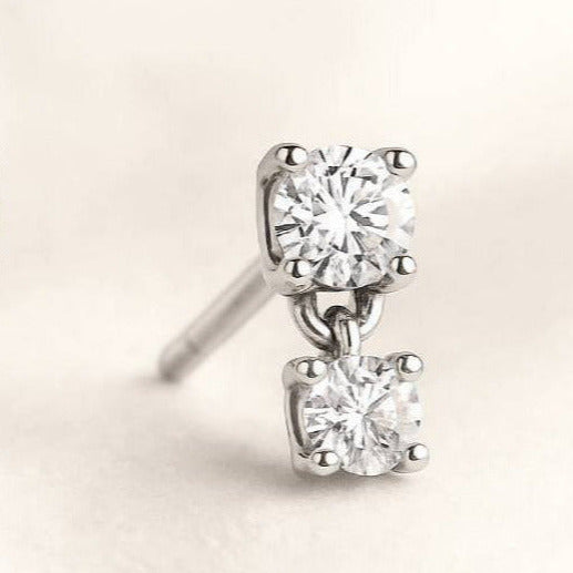 Pair of diamond stud earrings on a light beige background