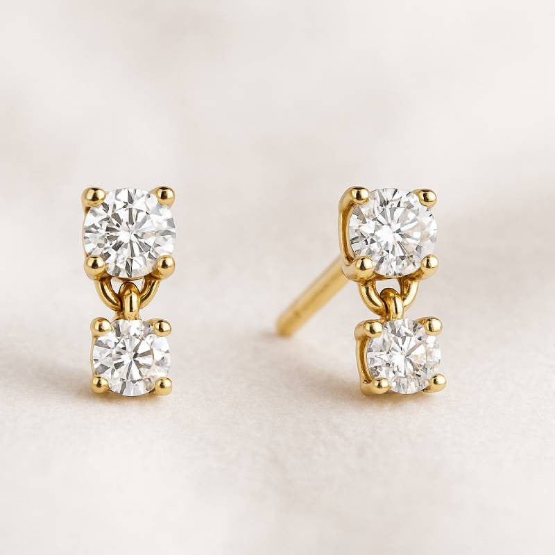 Gold earrings with diamonds on a light beige background