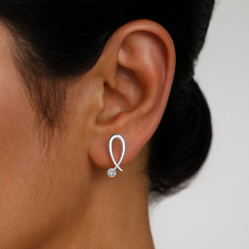 gold earring with a small diamonds worn by a person on a plain background