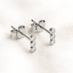 stud earrings with diamonds on a light pink background