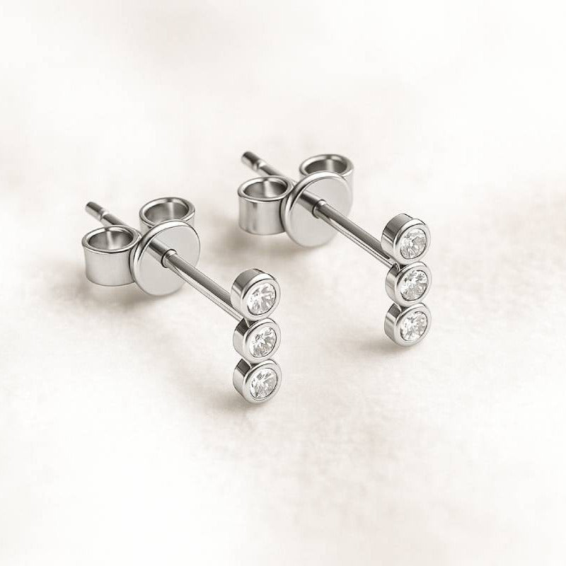 stud earrings with diamonds on a light pink background