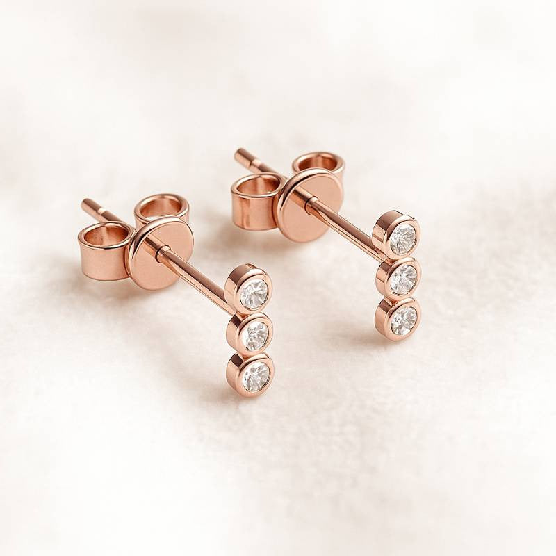 Rose gold stud earrings with diamonds on a light background