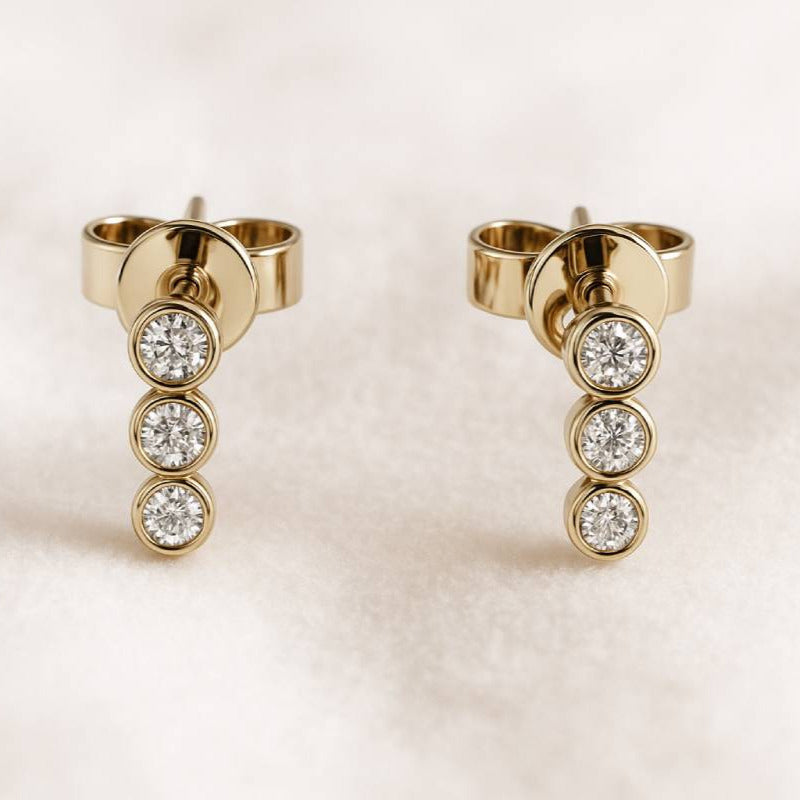 Gold earrings with diamond stones on a light background