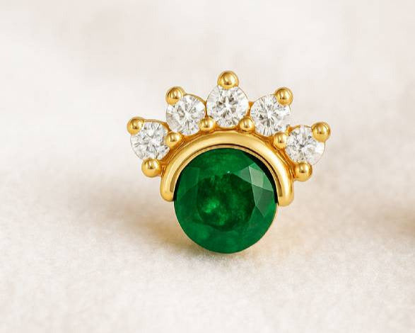 Gold earrings with green gemstones on a beige background