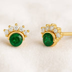 Gold earrings with green gemstones on a beige background
