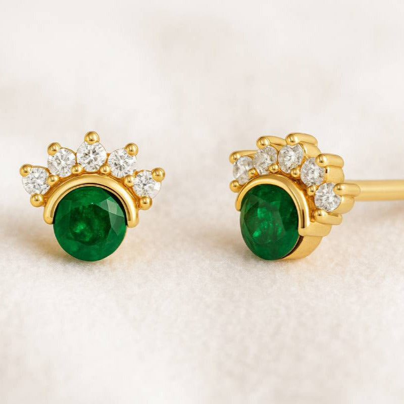 Gold earrings with green gemstones on a beige background