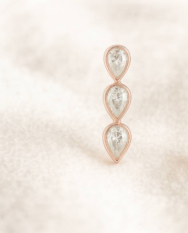 Rose gold earrings with clear gemstones on a soft beige background