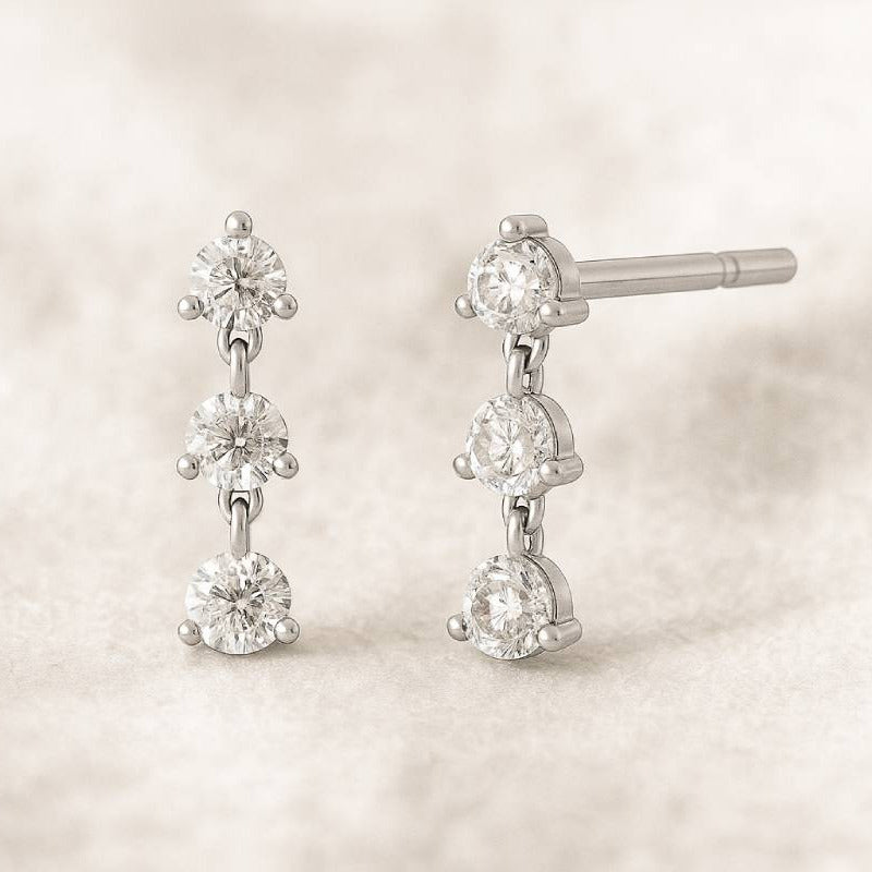 Pair of diamond earrings on a soft beige background
