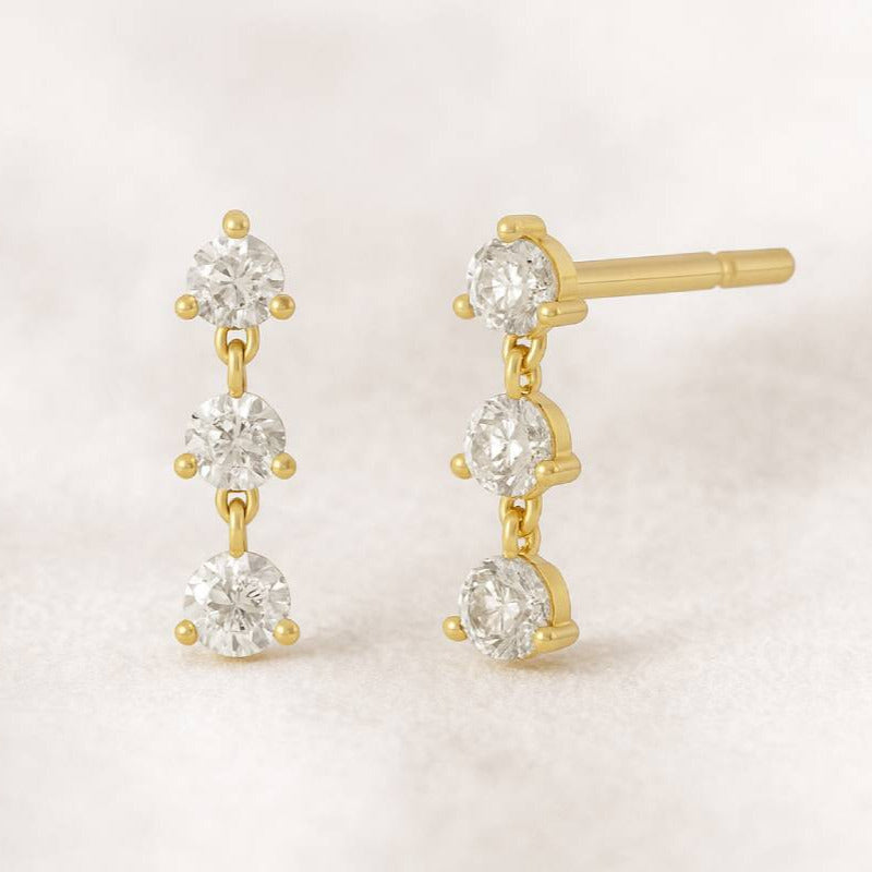 Gold and diamond earrings on a light background