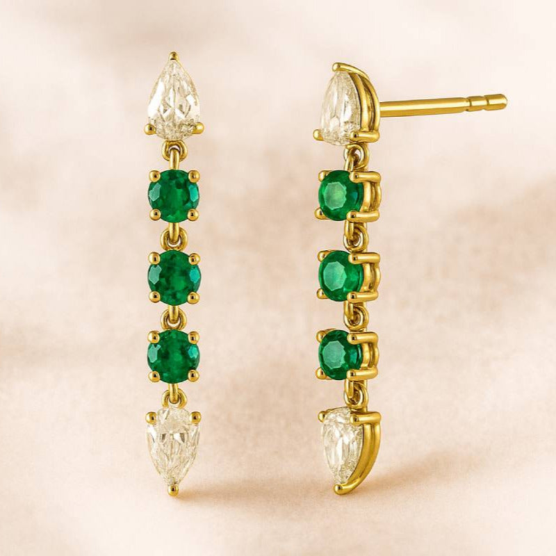 Gold earrings with green gemstones on a beige background