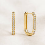 Gold hoop earrings with diamond accents on a light beige background