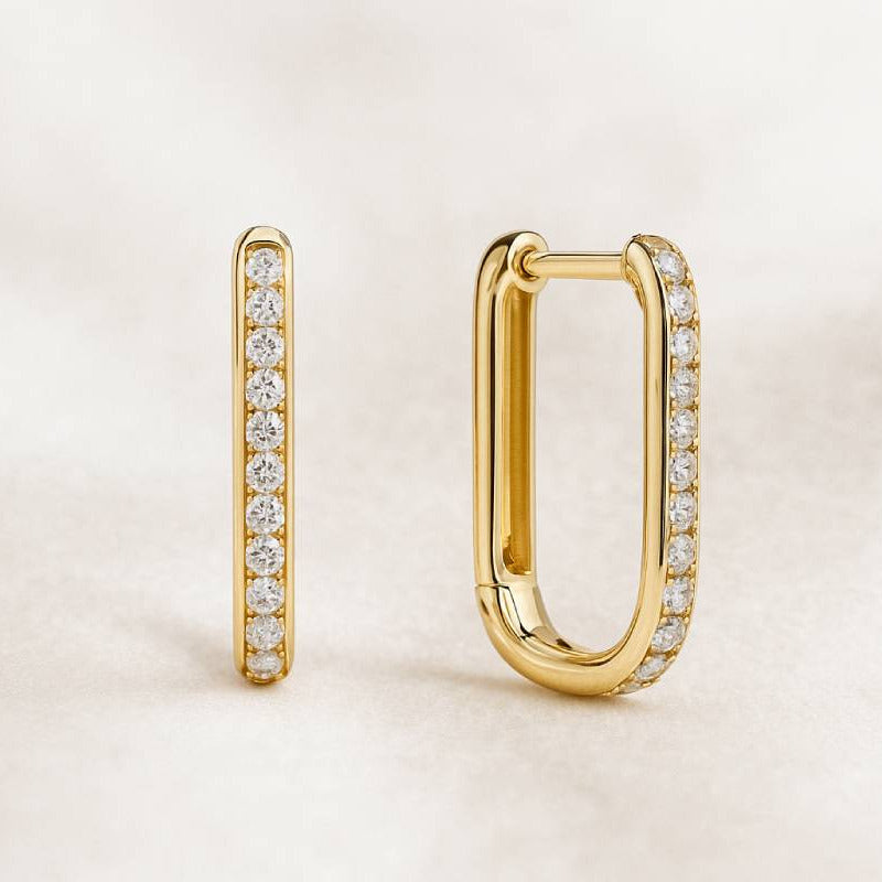 Gold hoop earrings with diamond accents on a light beige background