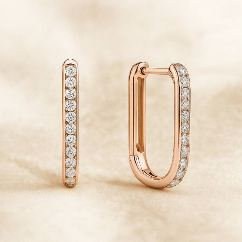 Rose gold hoop earrings with embedded diamonds on a beige background