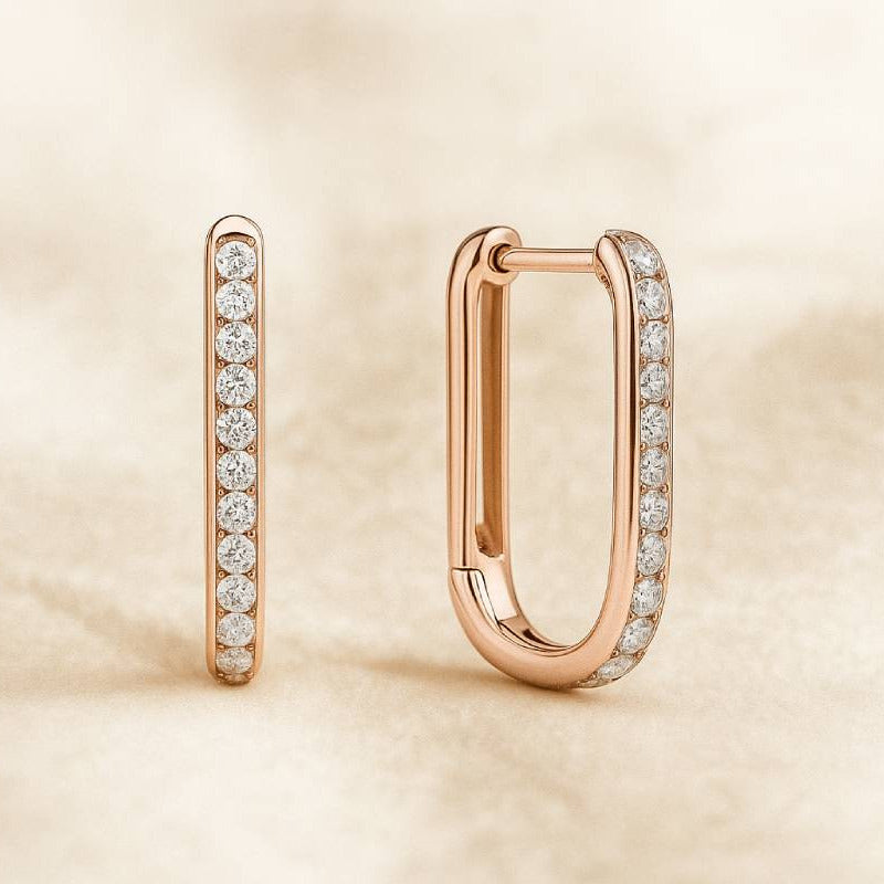 Rose gold hoop earrings with embedded diamonds on a beige background