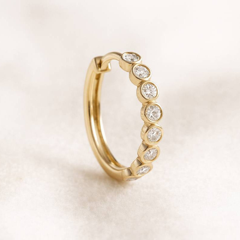 Gold earring with clear stones on a beige background