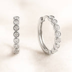 Pair of gold hoop earrings with embedded stones on a light background