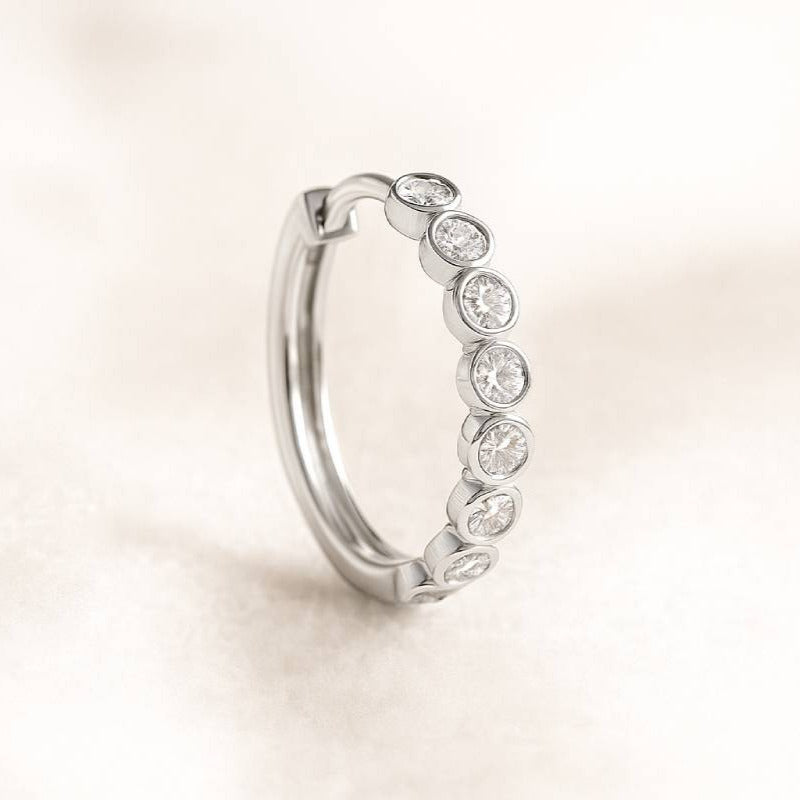 hoop earring with embedded diamonds on a light beige background