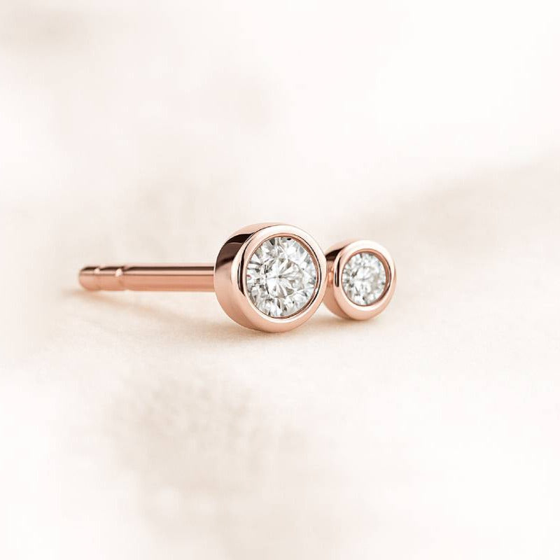 Rose gold earrings with clear gemstones on a light pink background