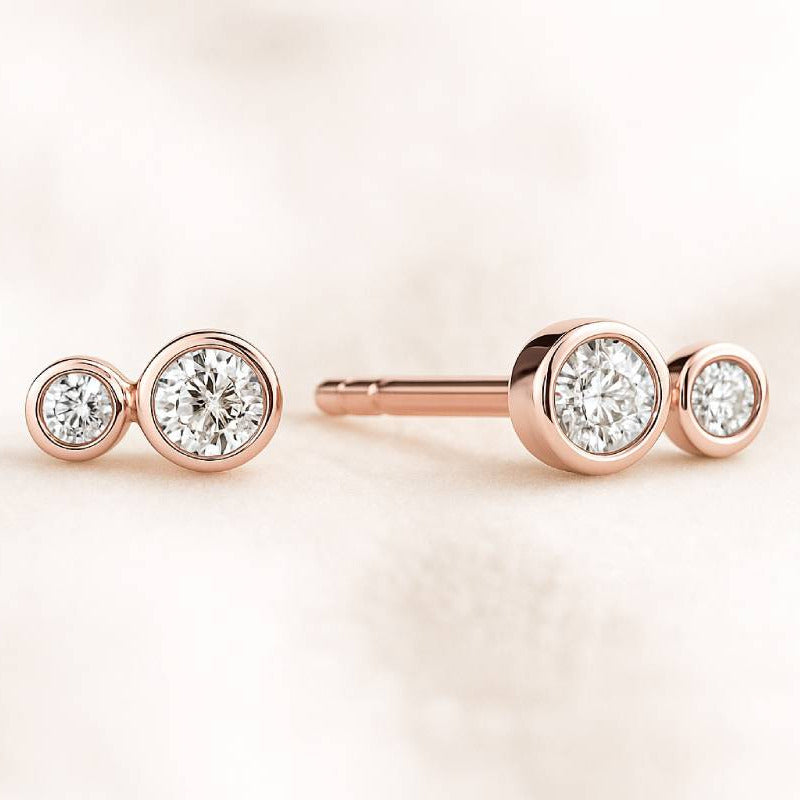 Rose gold earrings with clear gemstones on a light pink background