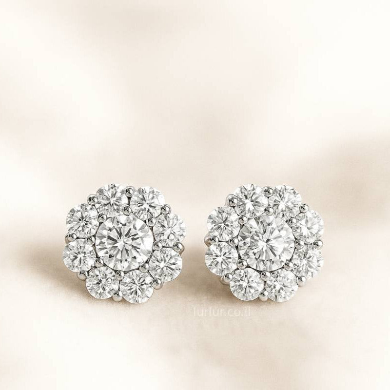 Pair of floral earrings with clear gemstones on a beige background