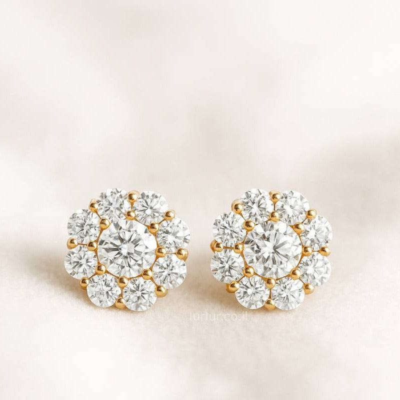 Pair of gold and crystal stud earrings on a light beige background