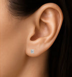 Close-up of an ear wearing a diamond stud earring with a dark background