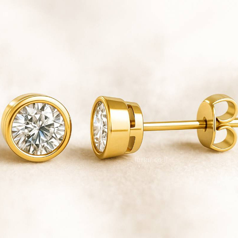Gold diamond stud earrings on a beige background